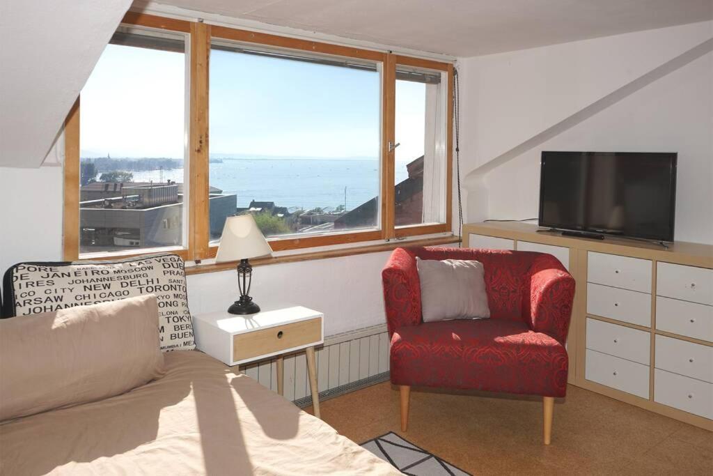 a living room with a red chair and a television at Haus Bregenz Apartment Festspiele in Lochau