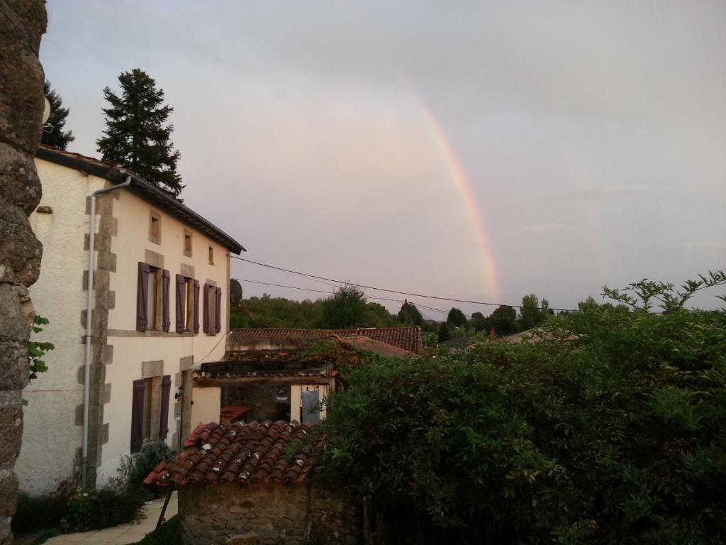 een regenboog in de lucht boven een gebouw en een huis bij 38 Friaudour in Saint-Pardoux