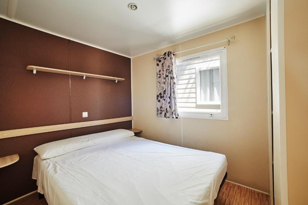a small bedroom with a bed and a window at Alannia Costa Dorada in Platja de l’Almadrava