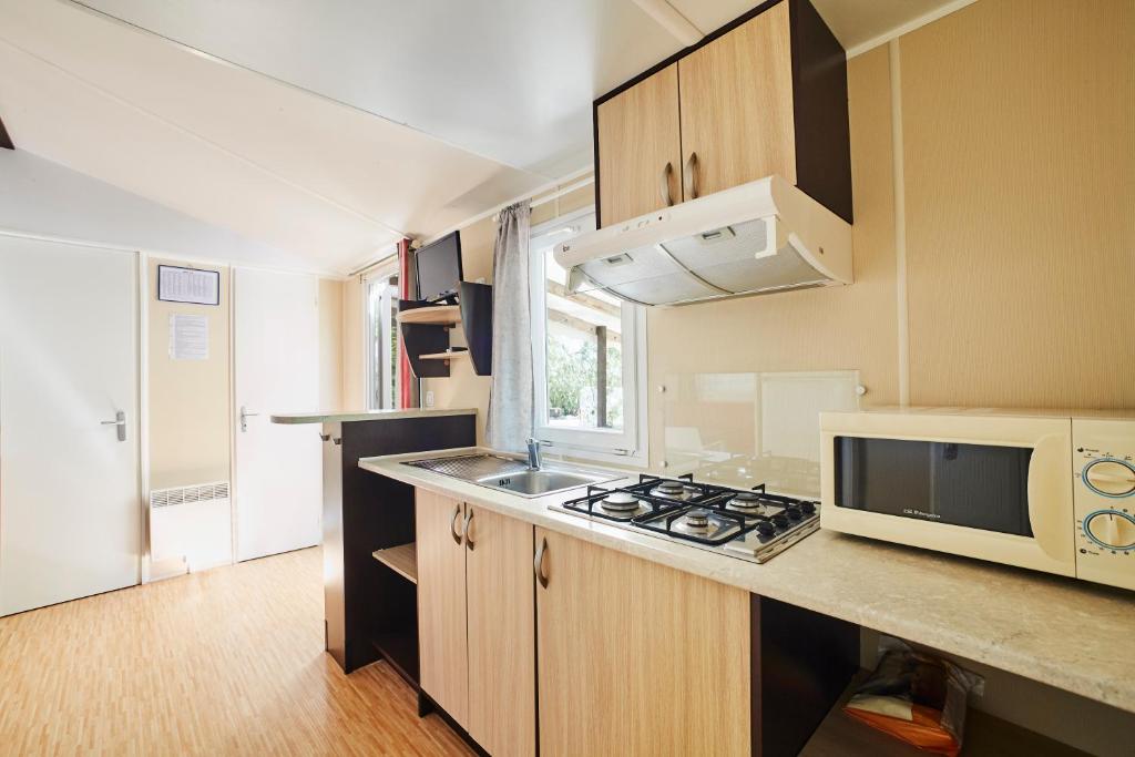 a small kitchen with a microwave and a stove at Alannia Costa Dorada in Platja de l’Almadrava