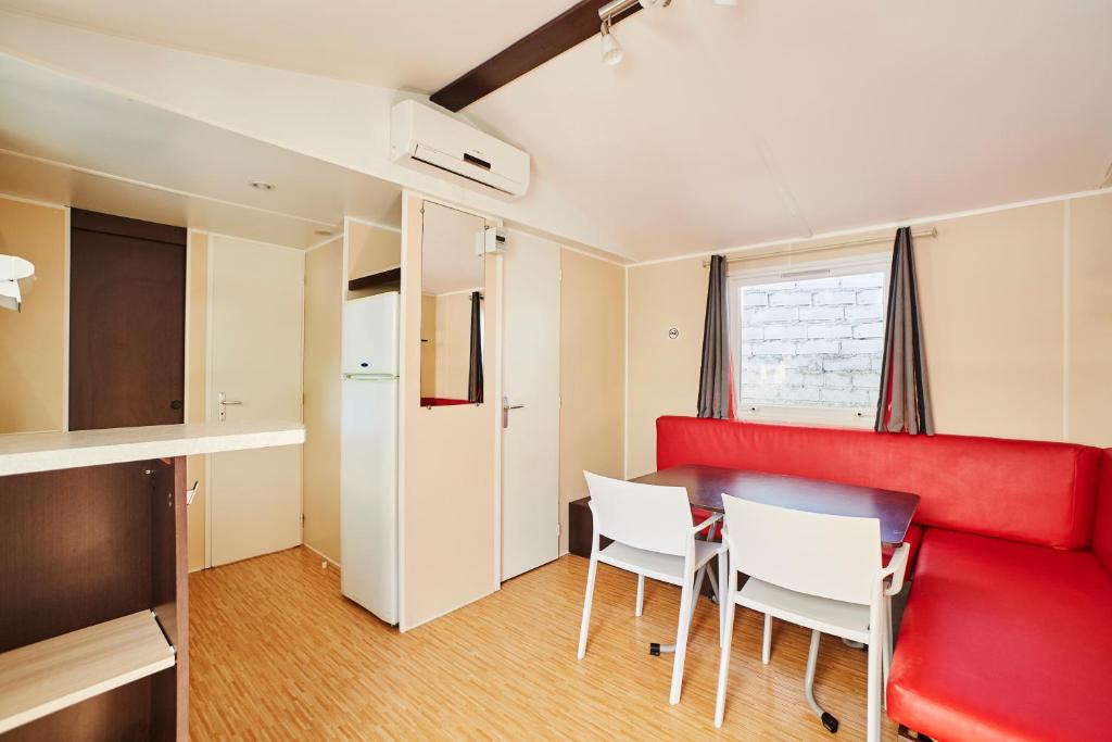 a room with a red couch and white chairs at Alannia Costa Dorada in Platja de l’Almadrava