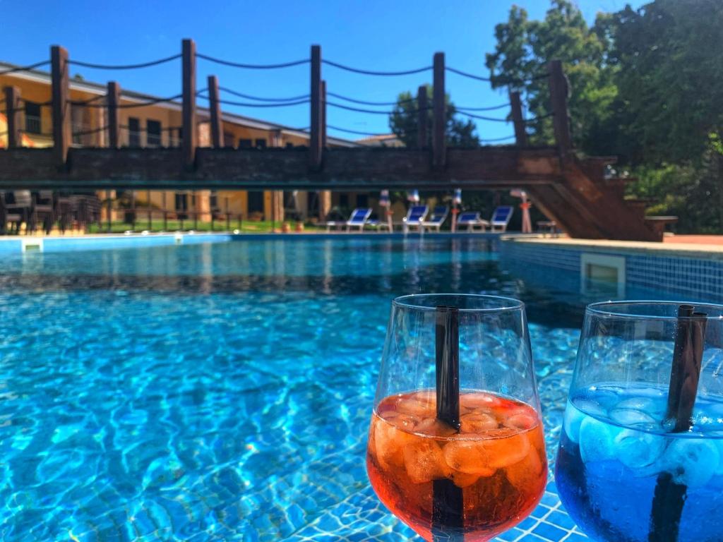 瓦雷多利亞的住宿－Hotel La Ciaccia，两个玻璃杯坐在游泳池旁的桌子上