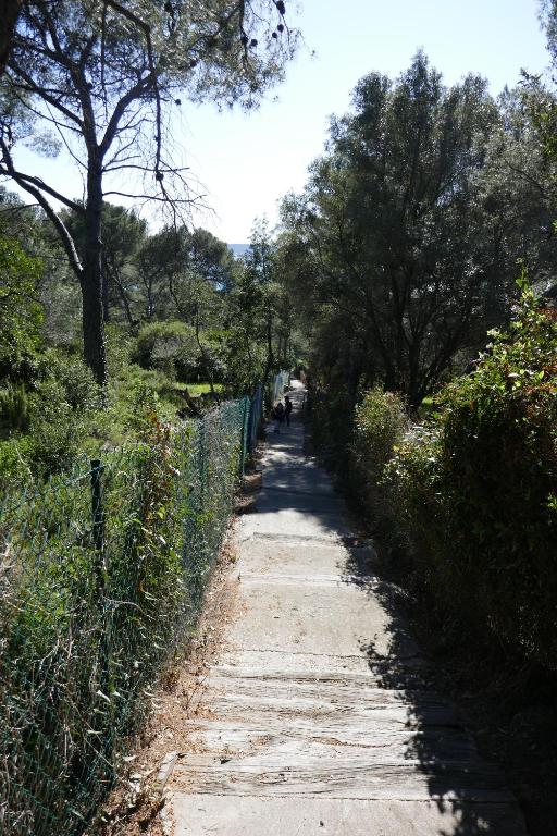 a dirt path with a fence and trees on it at Bel Appartement accès direct mer; L&#39;Almanarre, HYERES in Hyères