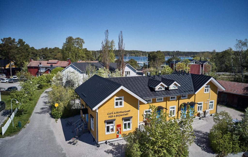 une maison jaune avec un toit noir dans une rue dans l'établissement Köpmans, à Nauvo