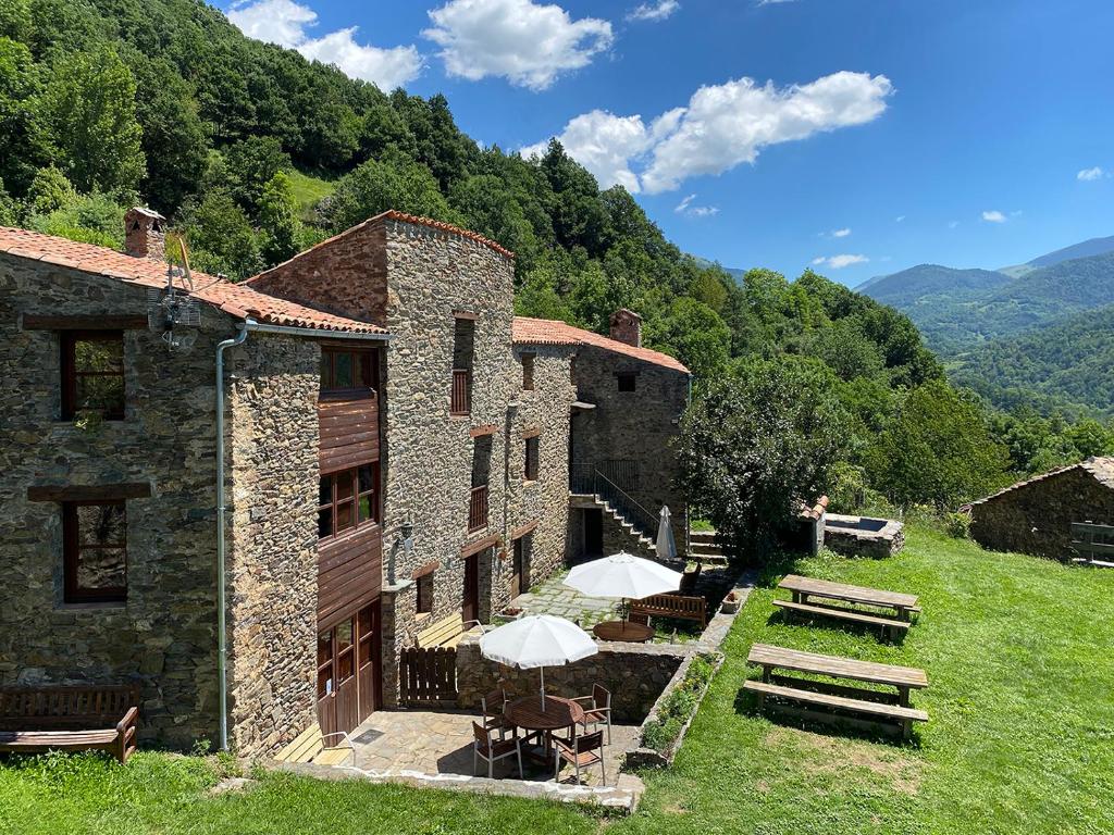 un edificio con mesas y sombrillas en el césped en Can Coderch en Ribes de Freser