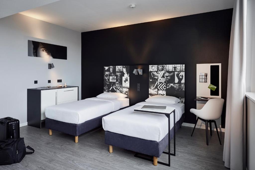 ビーレフェルトにあるLÉGÈRE EXPRESS Bielefeldのベッド3台、デスク、椅子が備わる客室です。