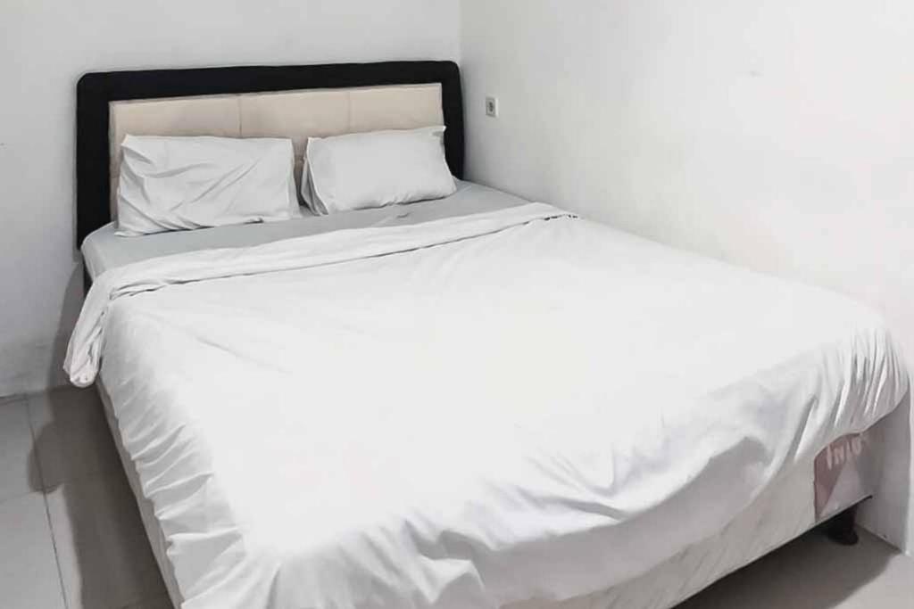 een wit bed met witte lakens en kussens bij Ancol Homestay in Jakarta
