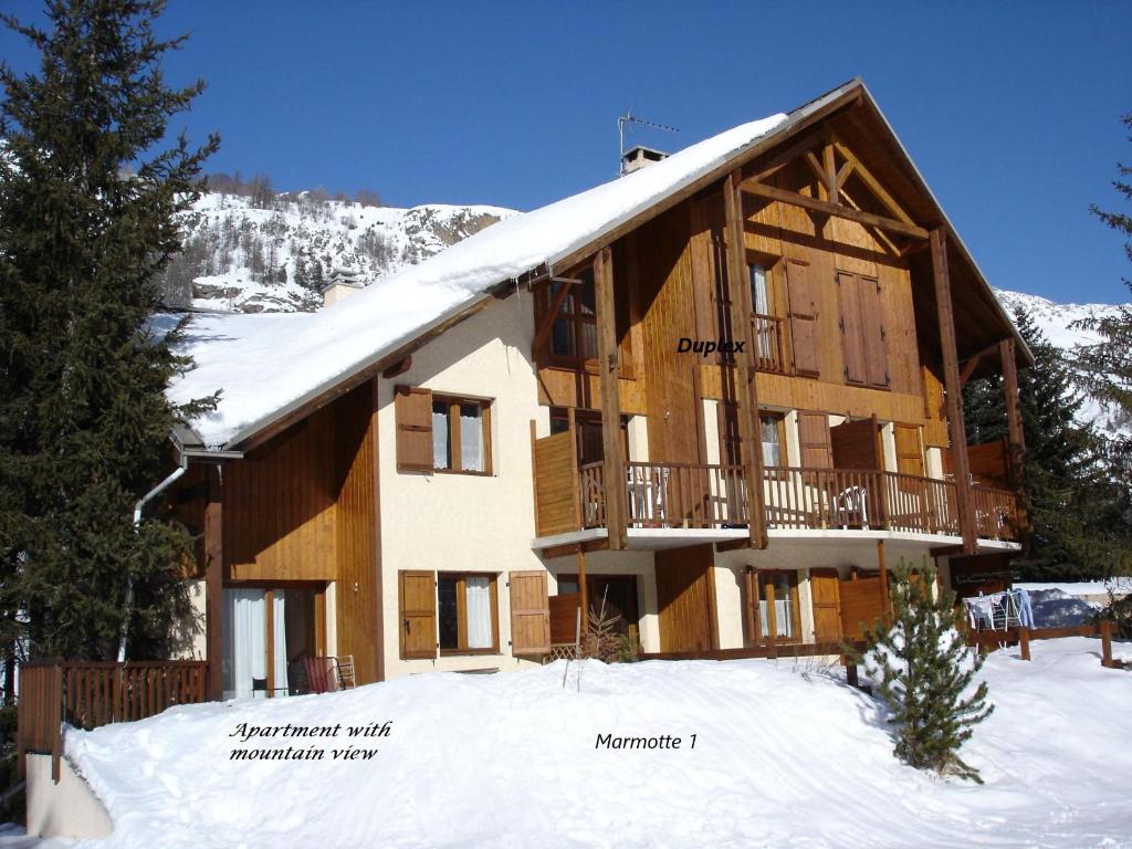 duży drewniany dom z śniegiem na dachu w obiekcie Marmotte Le Monêtier Apartment w mieście Le Monêtier-les-Bains