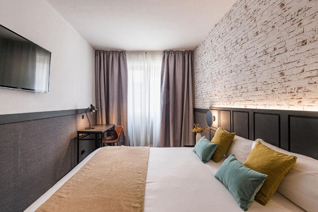 a hotel room with a bed and a brick wall at BYPILLOW San Mamés in Bilbao