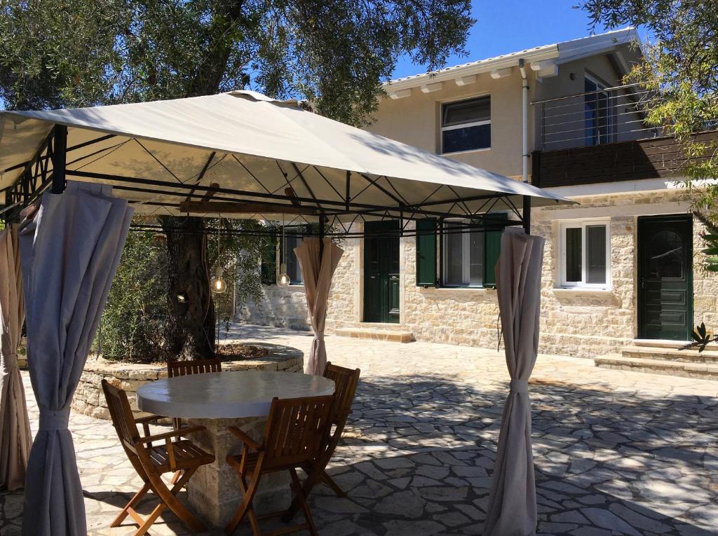 une table et des chaises sous un parasol devant une maison dans l'établissement Villa Antonis, à Lakka
