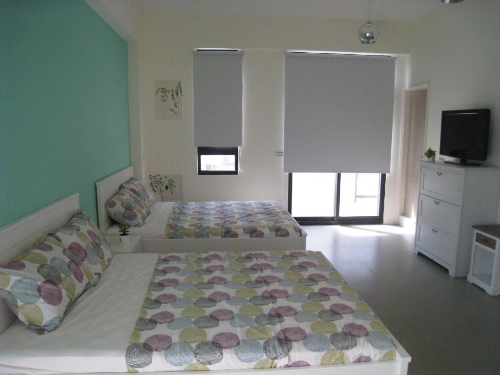 a bedroom with two beds and a flat screen tv at Penghu 123 V-Stone in Magong