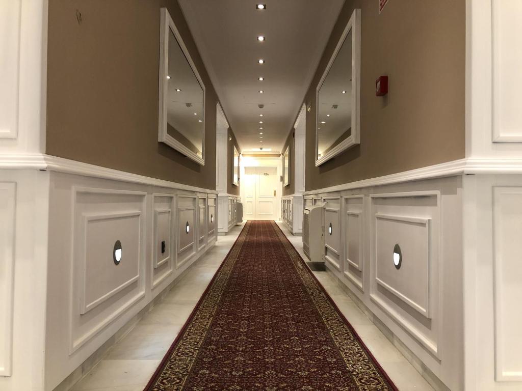 um corredor com um tapete no chão de um edifício em Hotel Las Acacias em Puente Genil