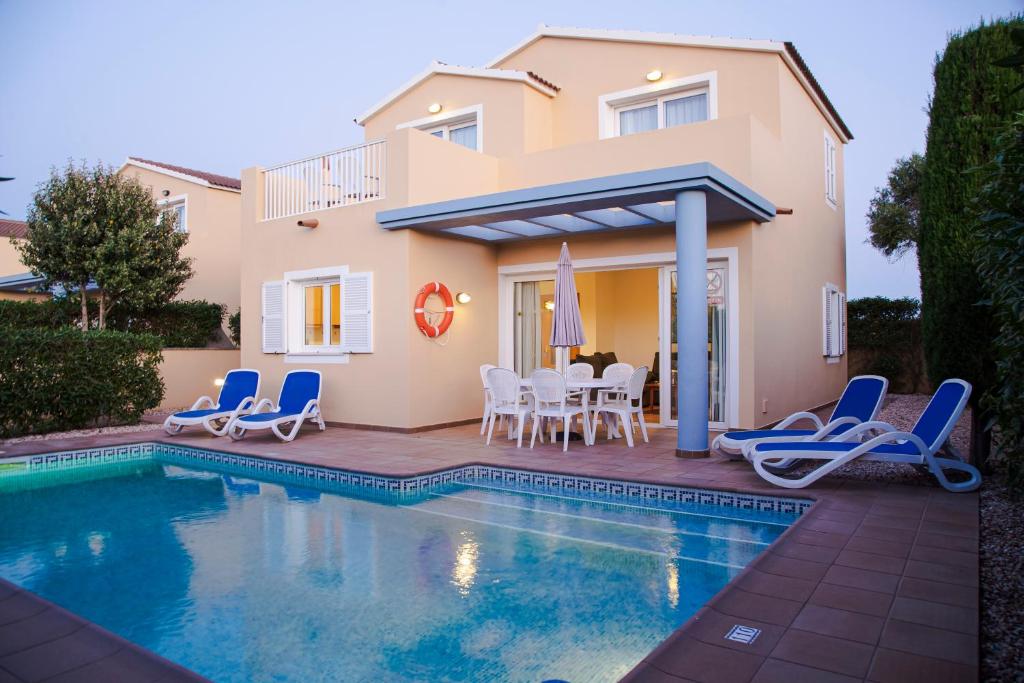 a villa with a swimming pool in front of a house at Sagitario Villas in Son Carrio