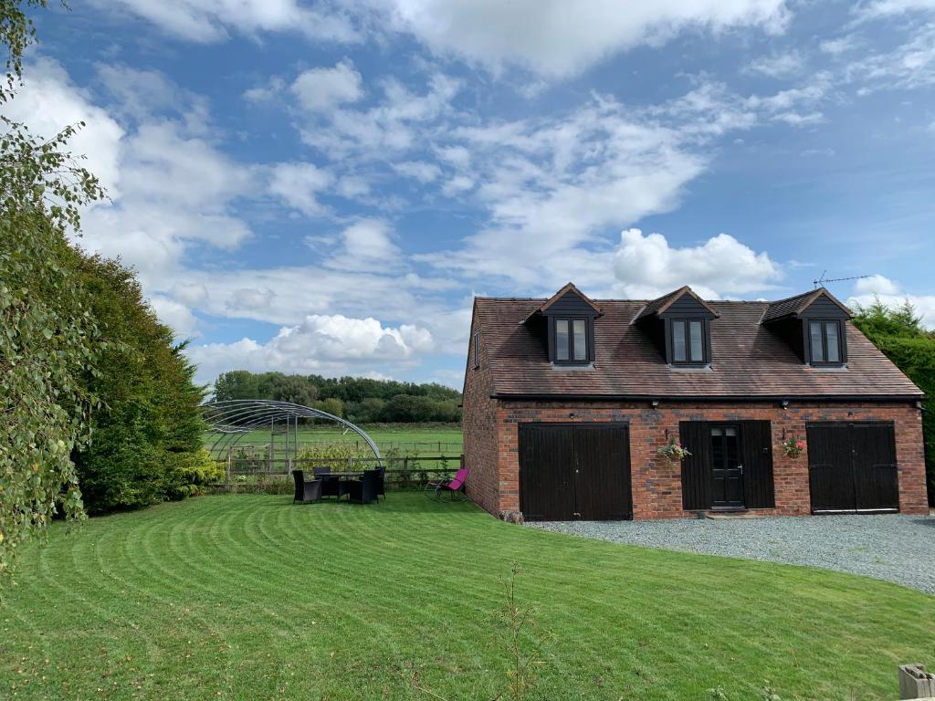 een stenen huis met ramen aan de zijkant van een tuin bij Meadow View @ Glebe Barn in Pershore