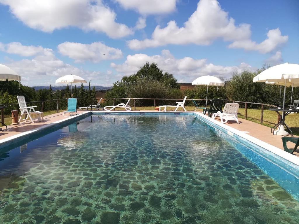 uma grande piscina com cadeiras e guarda-sóis em Casale Giuncheto em Pilonico Paterno