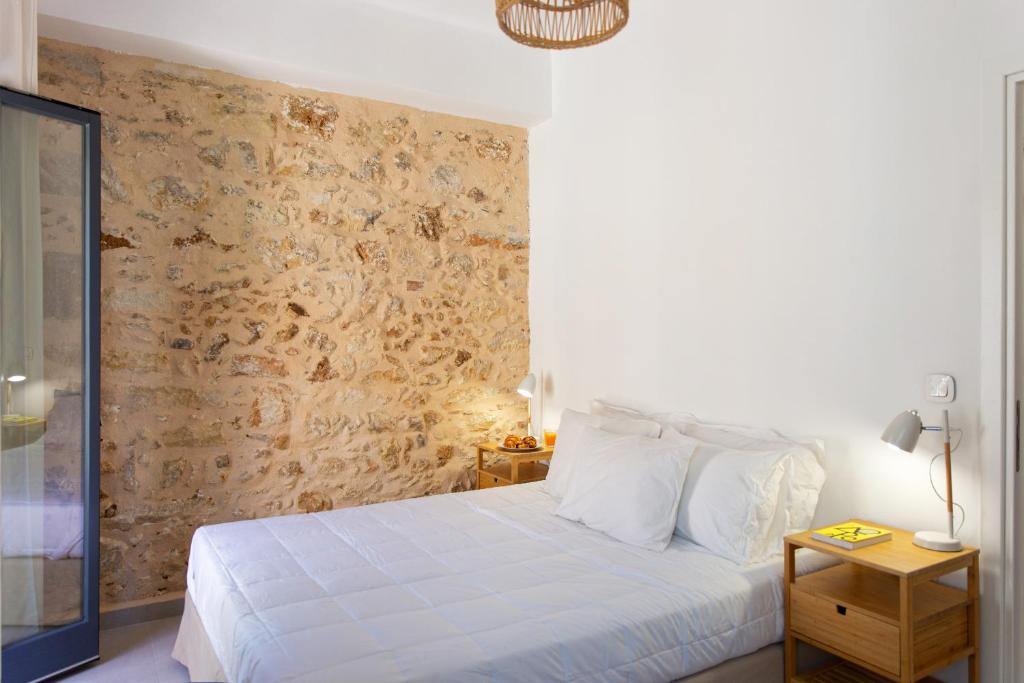ein Schlafzimmer mit einem weißen Bett und einer Wand in der Unterkunft Orestis downtown home in Rethymno