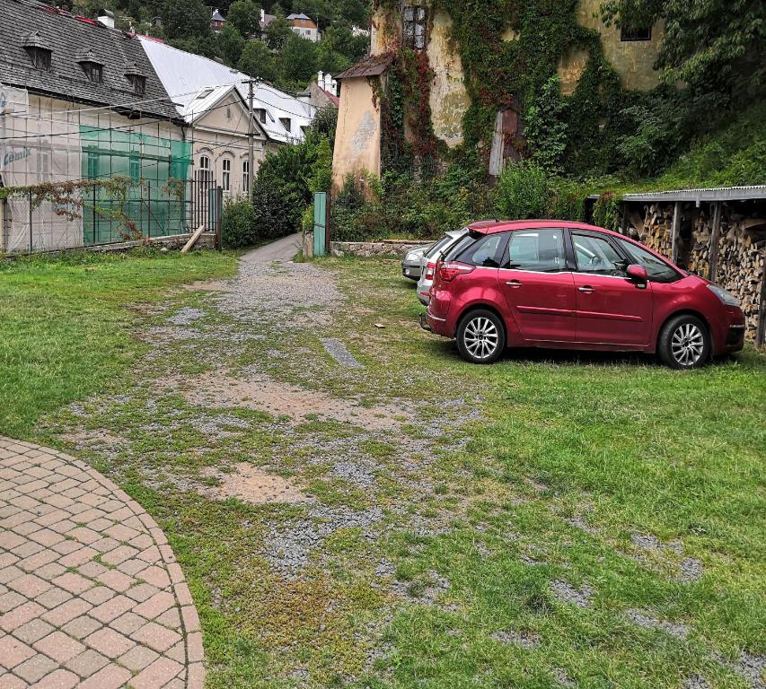 a red car parked in the grass in a yard at Hostel Skautský dom in Banská Štiavnica