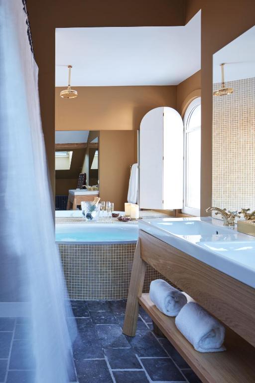 a bathroom with a tub and a sink and a mirror at Grand Hotel Soleil d'Or in Megève