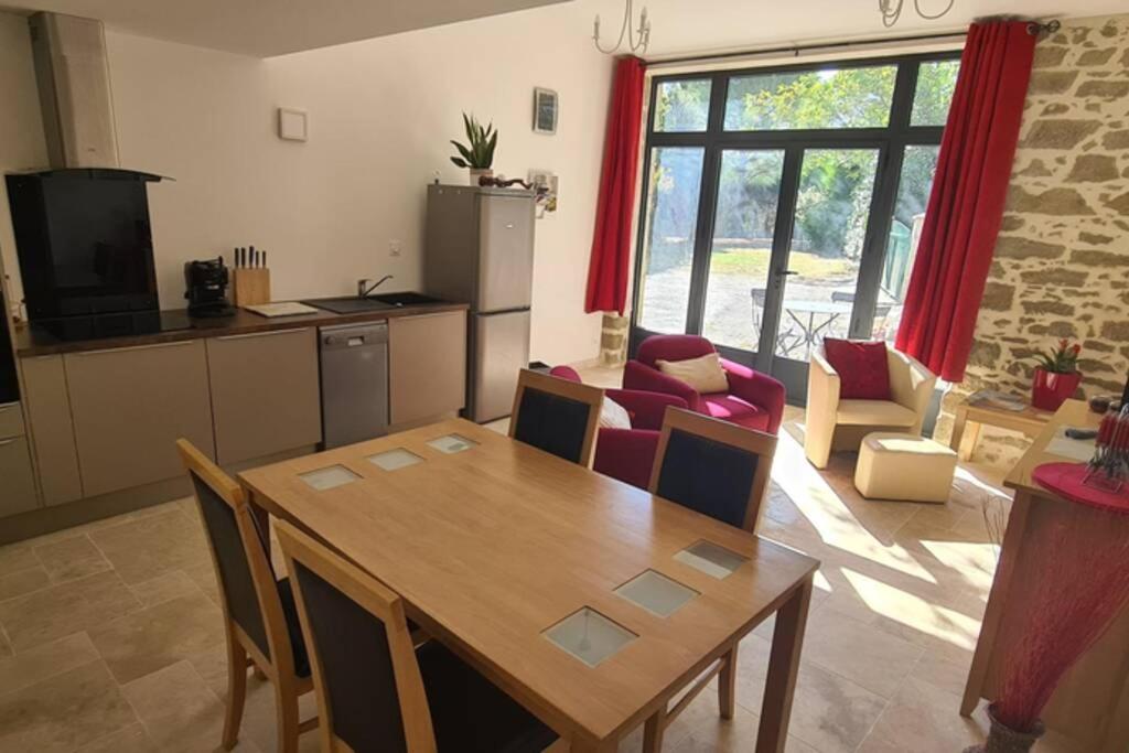 a living room with a wooden table and a kitchen at Ruby - Gîte 2 chambres dans vieux prieuré près de Carcassonne in Sainte-Eulalie