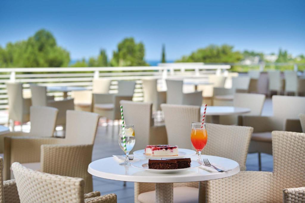 a table with a piece of cake and two glasses at Hotel Albatros Plava Laguna in Poreč