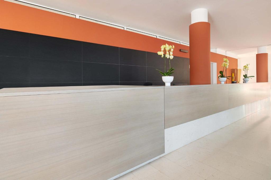 an office lobby with a reception counter with orange and black walls at Hotel Albatros Plava Laguna in Poreč