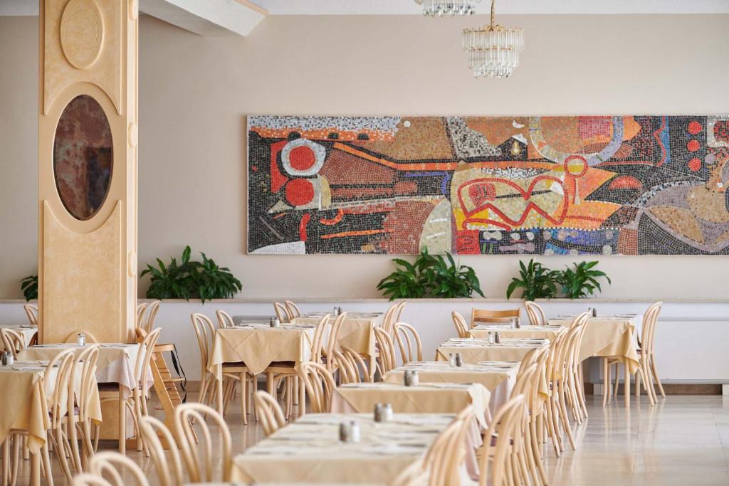 a dining room with tables and chairs and a large painting at Hotel Istra Plava Laguna in Poreč