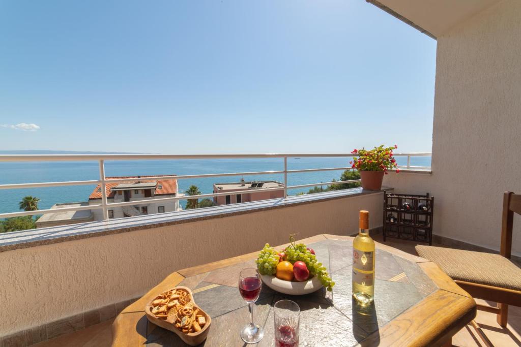uma mesa com uma taça de fruta e uma garrafa de vinho em Apartments Sunrise em Split