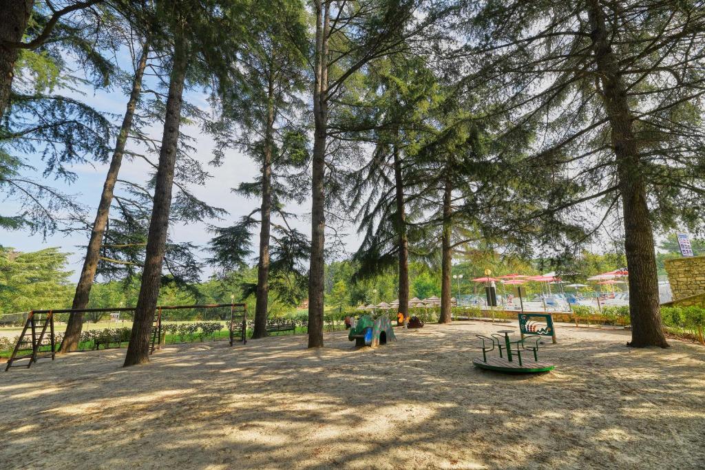 a park with a bunch of trees and a bench at Hotel Mediteran Plava Laguna in Poreč