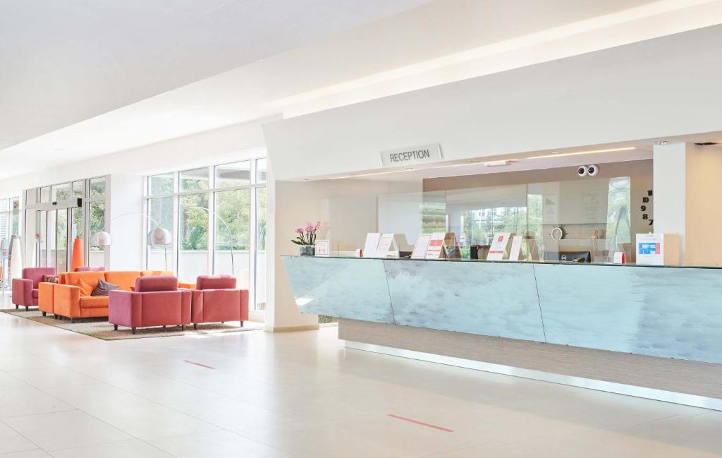 a lobby with orange chairs and a blue counter at Hotel Mediteran Plava Laguna in Poreč