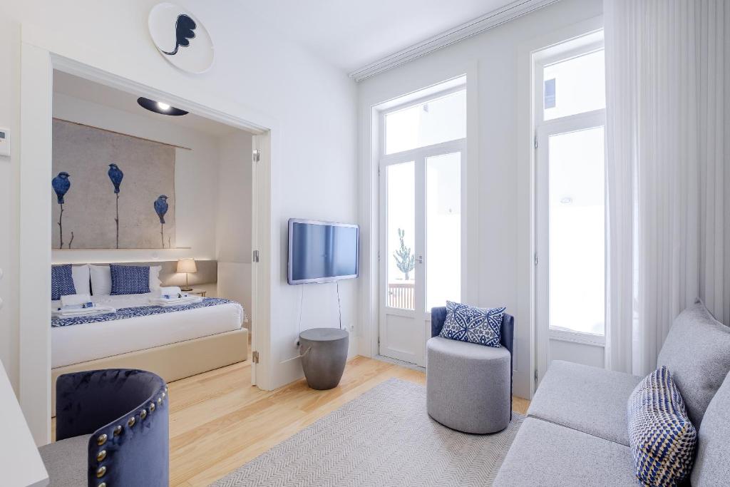 een witte kamer met een bed, een bank en een tv bij BOUTIQUE Rentals-Flores Terrace historical centre in Porto