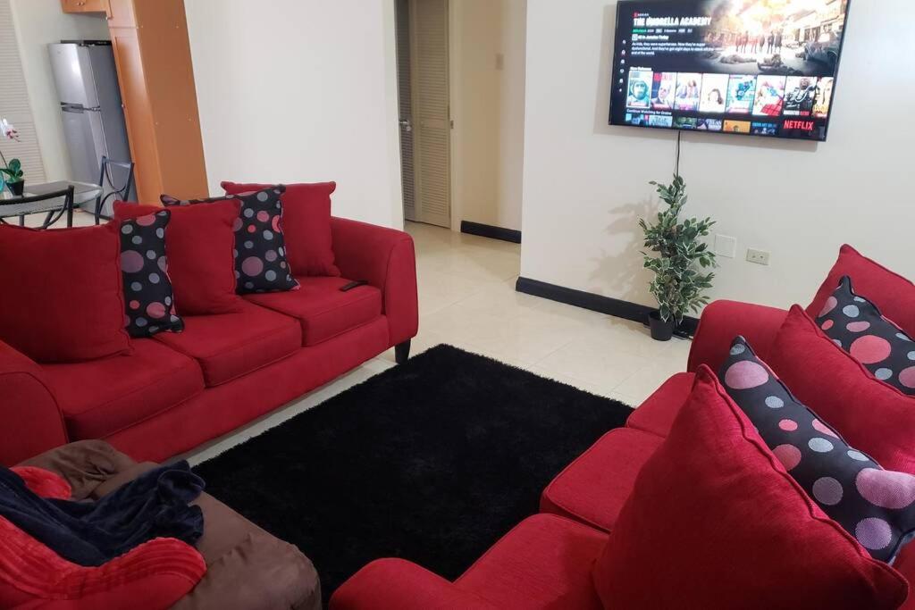 a living room with red couches and a person laying on the floor at Montego Bay Home Close to Resort Area and Airport in Montego Bay