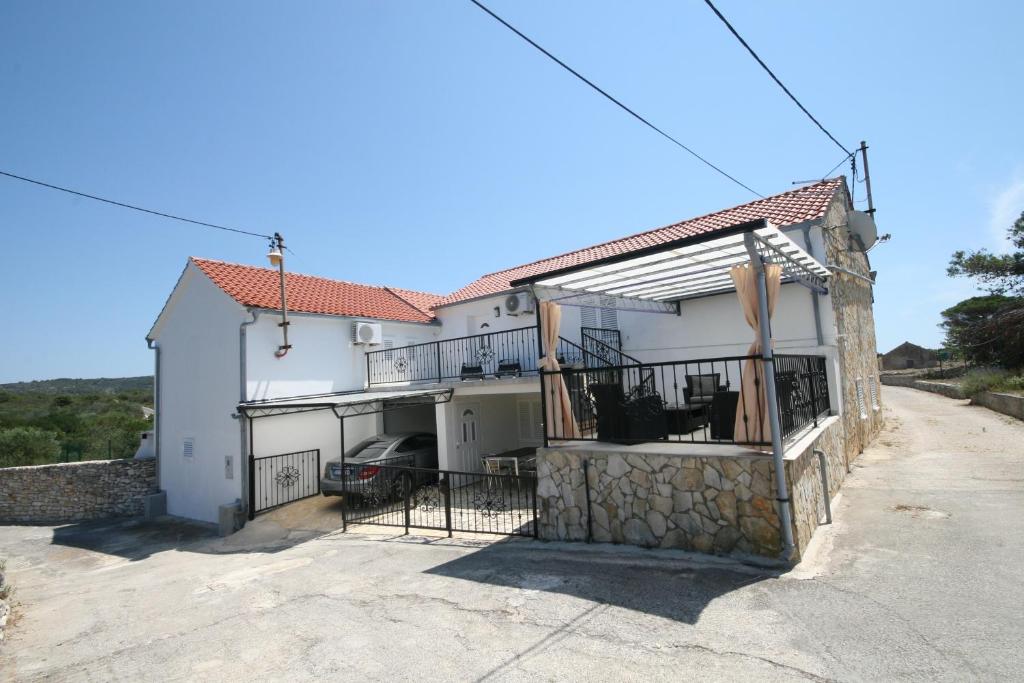 a white house with a balcony and a driveway at House Sakarun in Veli Rat