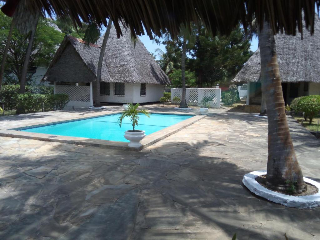 una piscina con una casa y una palmera en Glory Ocean Villas - Diani, en Diani Beach