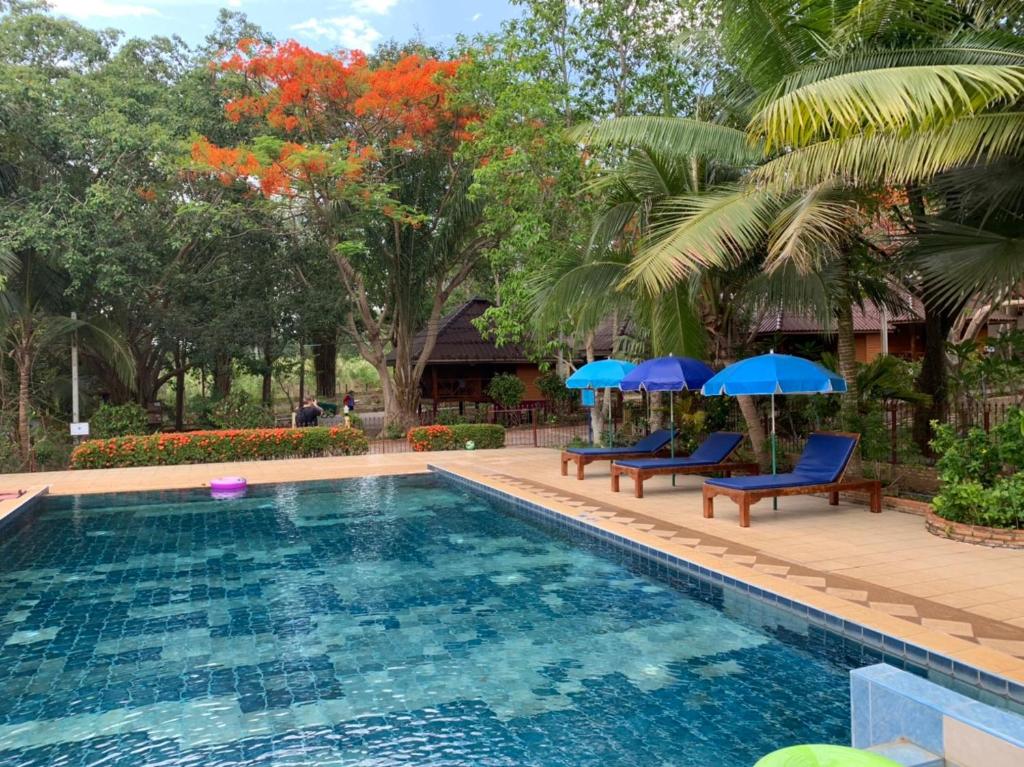 a swimming pool with blue chairs and umbrellas at Faasai Resort & Spa in Ban Nong Nam Khao