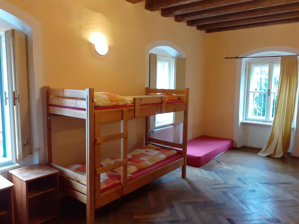 a room with two bunk beds and two windows at Hostel Skautský dom in Banská Štiavnica