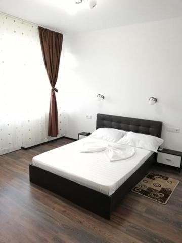 a bedroom with a bed with white sheets and a window at Red House in Orşova