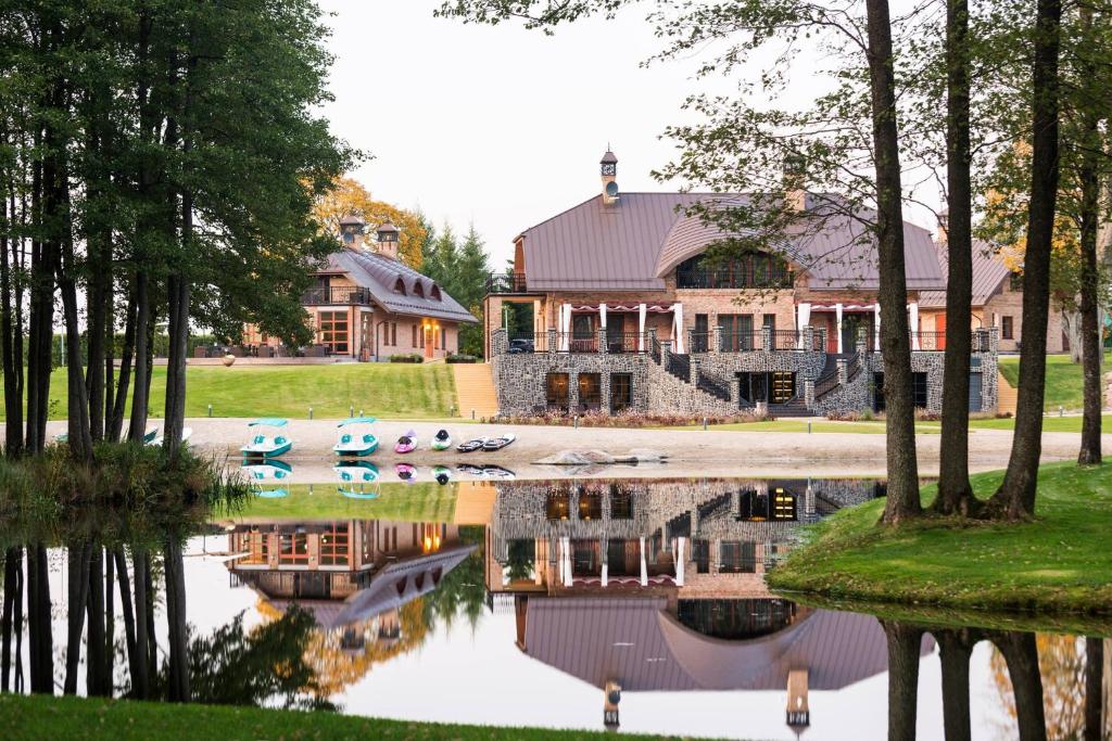 a house with a pond in front of it at Sala Resort Plateliai & SPA in Plateliai