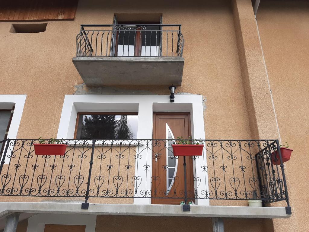 a building with a balcony with a door and a window at La Maison Trésallet in La Plagne Tarentaise