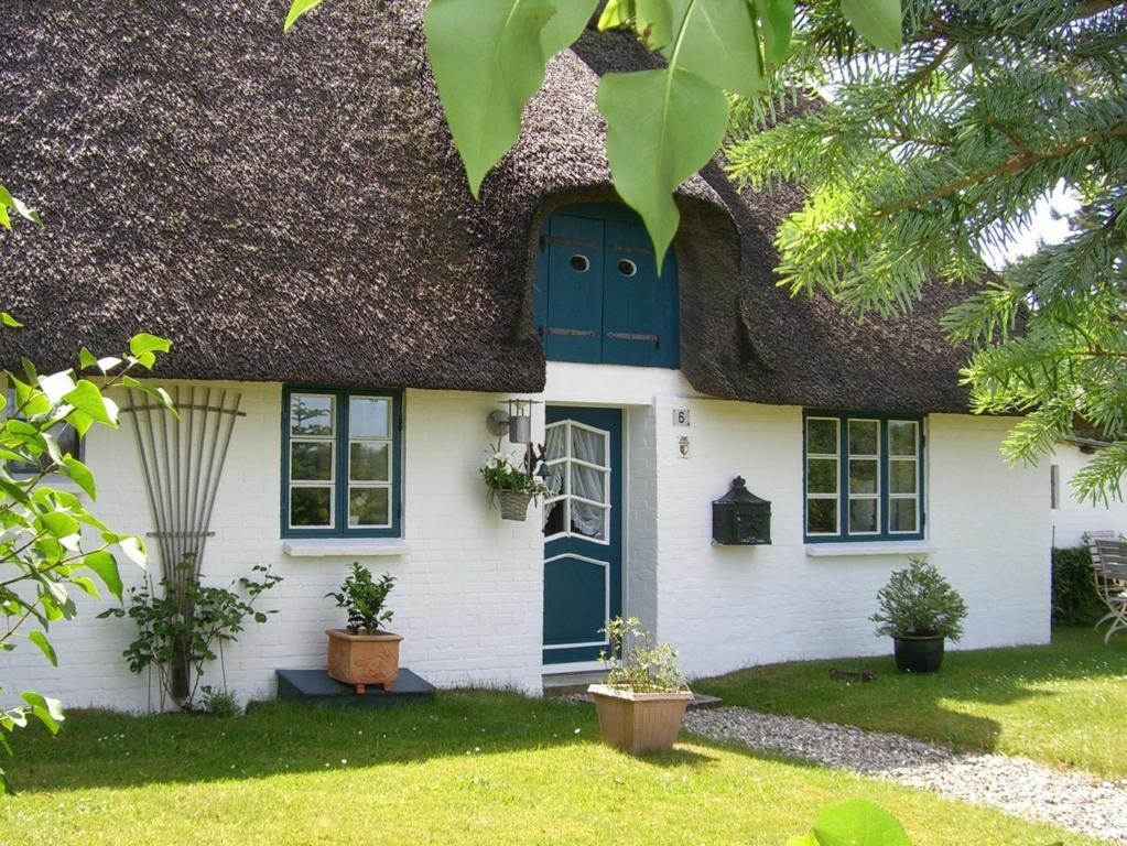 a thatch roof house with a blue door at Das Kätnerhaus Nordsee in Langenhorn