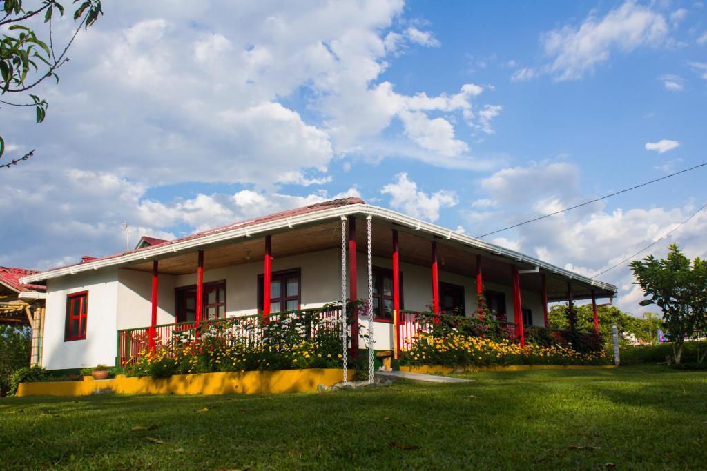 Casa blanca con persianas rojas y patio verde en Casa Laureles, en Filandia