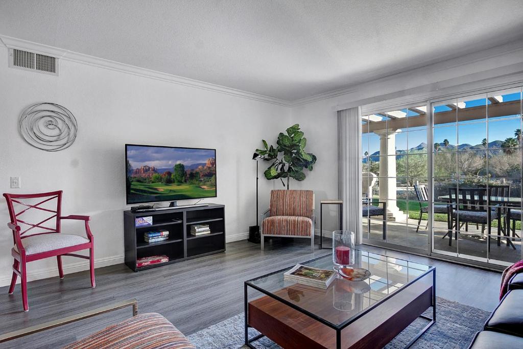 a living room with a tv and a table at Our Mesquite-Refreshed 1st floor nature preserve & mtn view condo! in Palm Springs