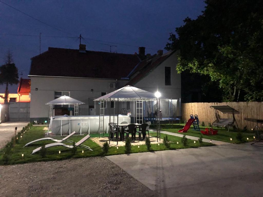 ein Haus mit einem Tisch und einem Spielplatz in der Nacht in der Unterkunft D&D apartments in Subotica