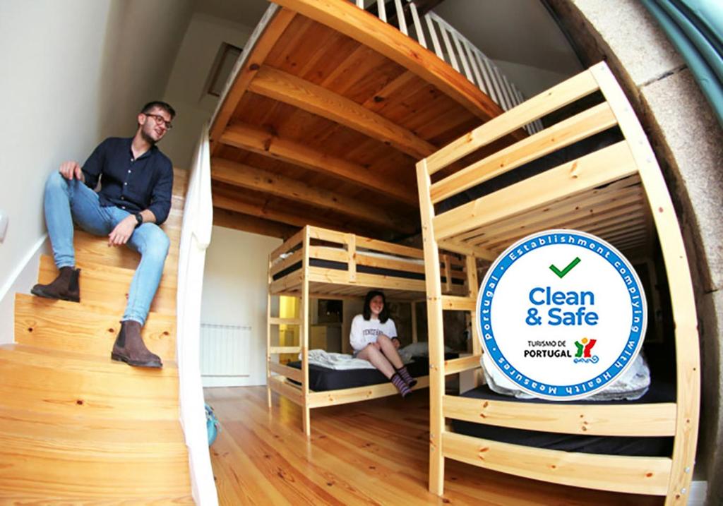 a man and woman sitting on bunk beds in a room at Onefam Ribeira by Hostel One in Porto