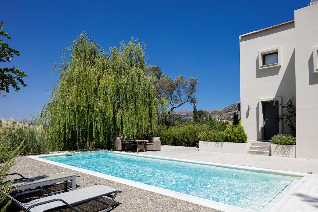a swimming pool in front of a white house at Tessera Villa, a Serene Escape in Nature with Pool, By ThinkVilla in Spílion