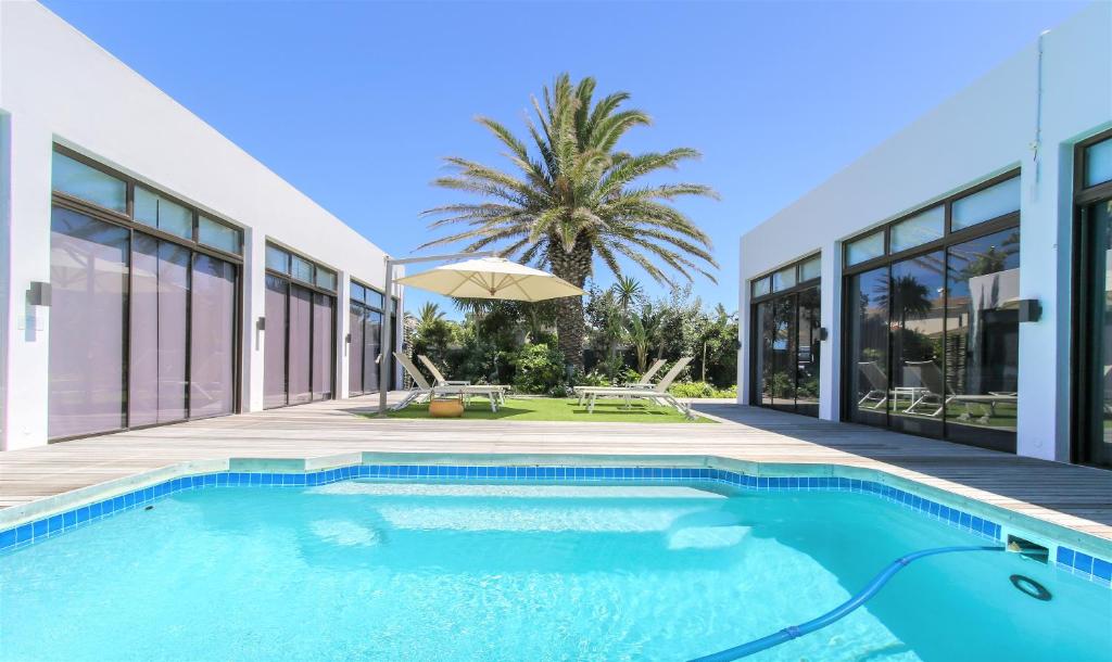 a swimming pool in front of a house at OCEAN BREEZE SUNSET BEACH - Cape Town in Cape Town