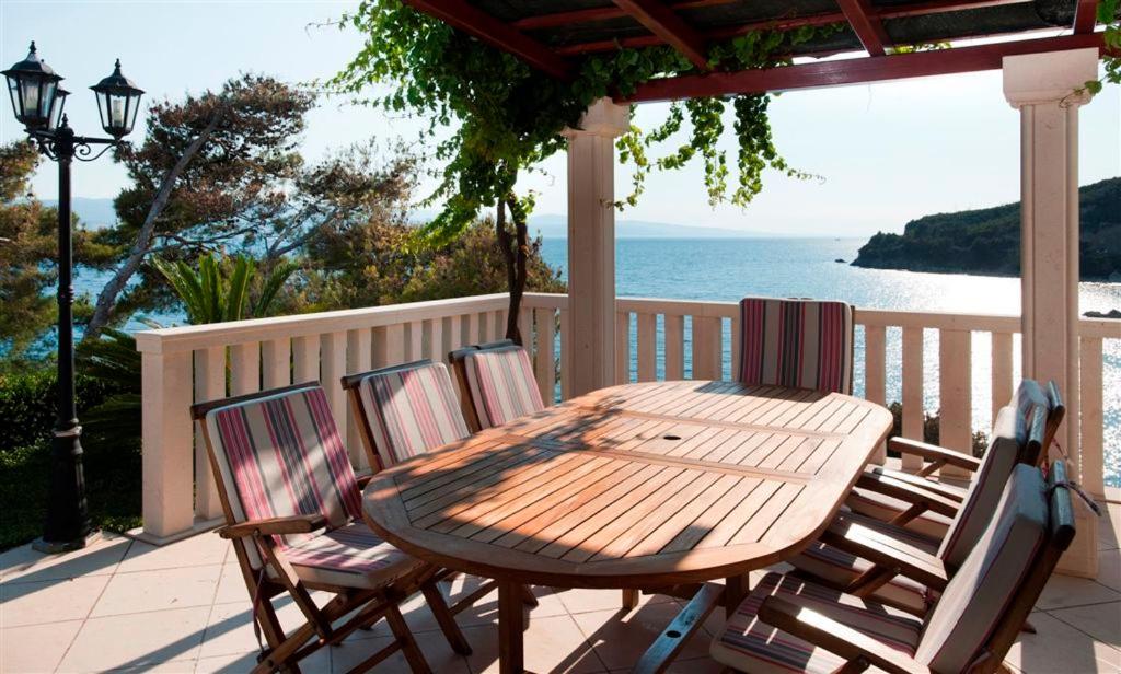 a wooden table and chairs on a deck with the ocean at Villa Luciana in Mimice