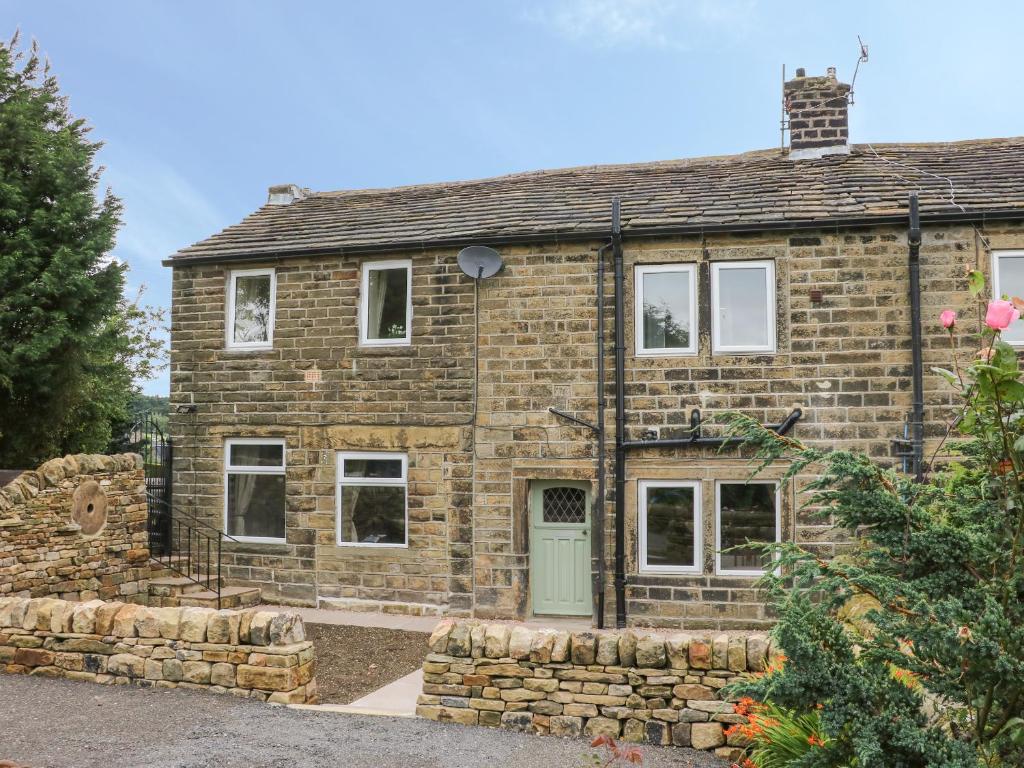 an old brick house with a green door at Hill Top Cottage in Keighley