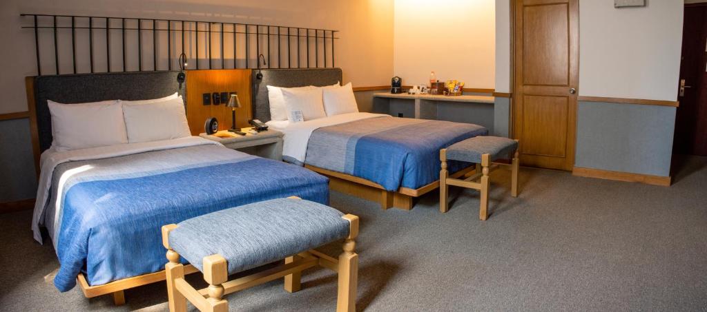 ケレタロにあるアシエンダ フリカ バイ ブリサスのベッド2台とテーブルが備わるホテルルームです。