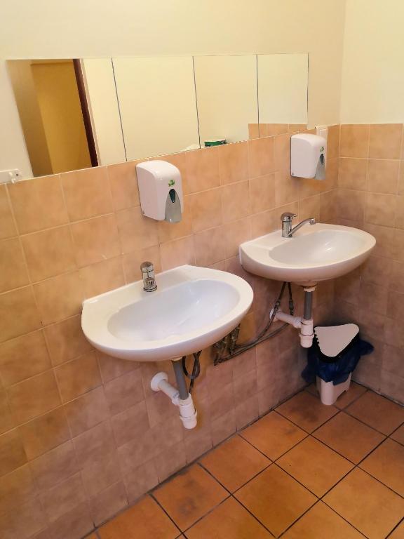 a bathroom with two sinks and mirrors on the wall at Hostel Skautský dom in Banská Štiavnica