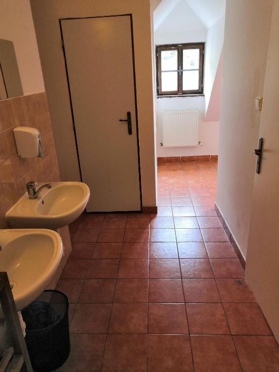 a bathroom with two sinks and a door at Hostel Skautský dom in Banská Štiavnica